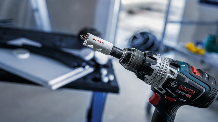 Bor tanpa kabel dengan mata bor lubang ditempatkan di dekat meja kerja.