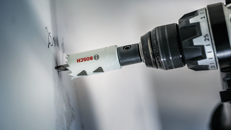 Bor lubang membuat potongan melingkar di dinding.