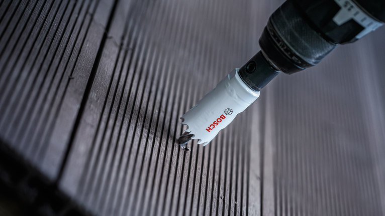 Mata bor gergaji lubang membuat potongan melingkar pada papan dek kayu.