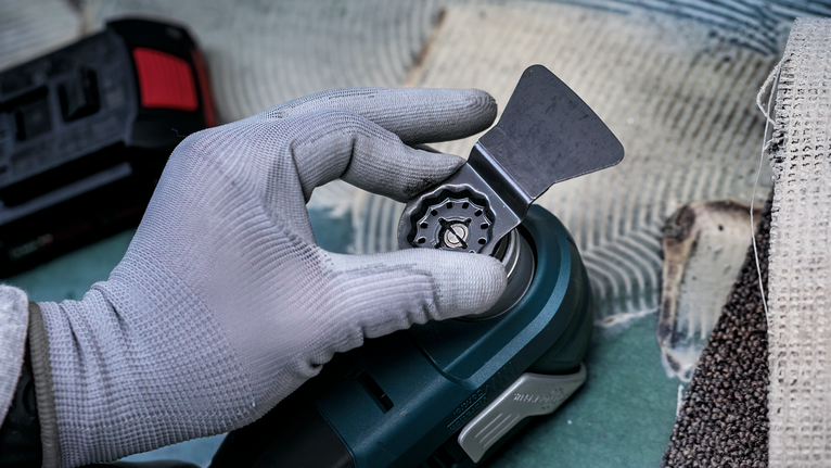 Seseorang yang mengenakan peralatan keselamatan memasang mata pisau pada perkakas listrik.