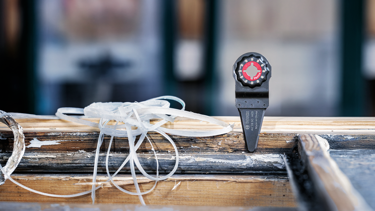 Alat multifungsi berosilasi yang terpasang pada bingkai jendela kayu yang sudah lapuk.