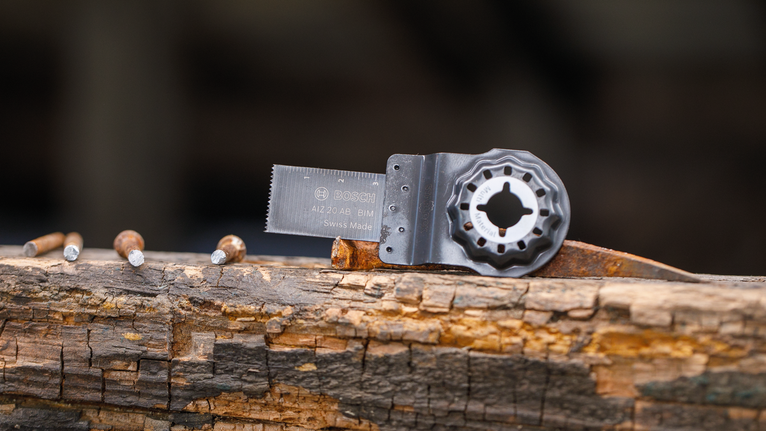 Pemasangan mata gergaji berosilasi yang dipasang pada balok kayu lapuk dengan paku.