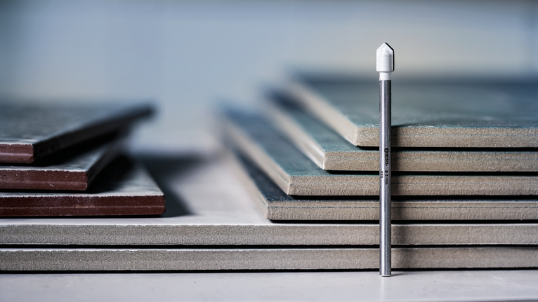 Mata bor ubin berlian berdiri tegak di depan tumpukan ubin keramik.