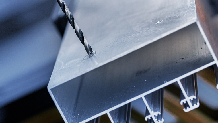 Mata bor membuat lubang pada balok logam.