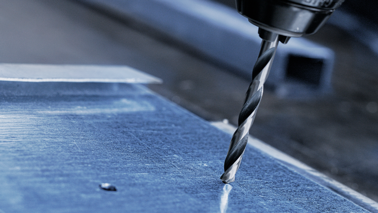 Bor listrik membuat lubang pada lembaran logam.