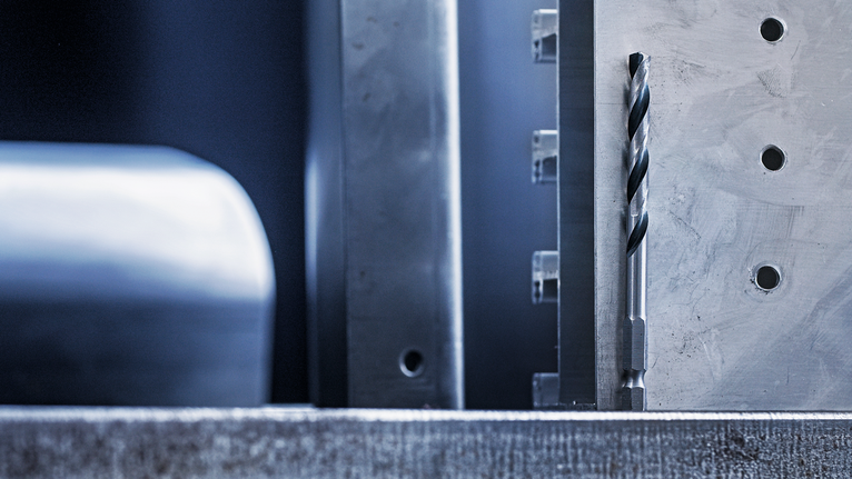 Mata bor logam yang diposisikan vertikal pada permukaan logam yang dikerjakan.