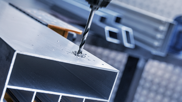 Bor membuat lubang pada balok logam di lingkungan industri.