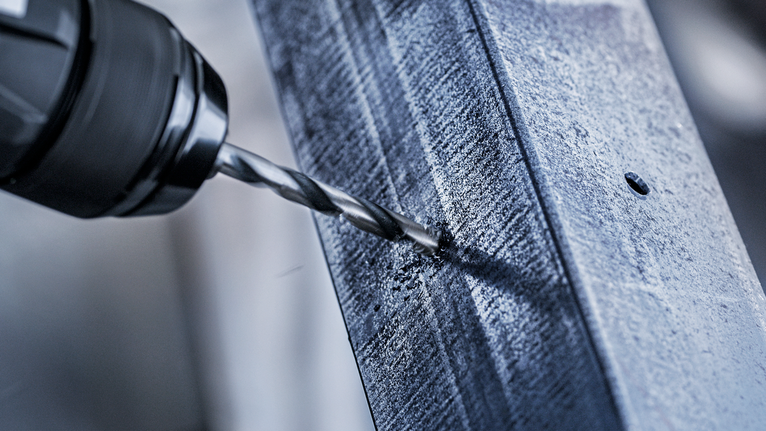 Bor listrik membuat lubang pada balok logam.