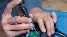 Seseorang menggunakan obeng untuk merakit komponen elektronik.